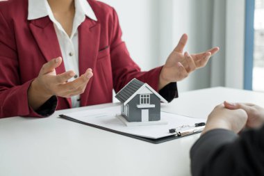 Ev modeli olan bir emlakçı ev sigortası almak için müşterilerle konuşuyor. Gayrimenkul Ev Sigortası.