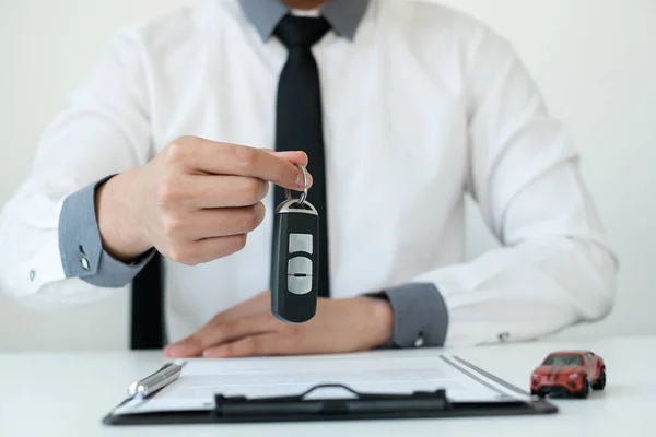 Car dealer businessman holding a car key. Car loan and insurance concept.
