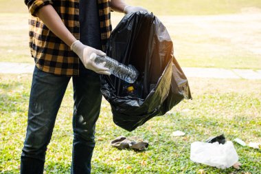 Adamın elleri plastik şişeleri topluyor, çöpleri siyah çöp torbalarına doldurup parkları temizliyor, kirlilikten kaçınıyor, çevreye ve ekosisteme dost oluyor..