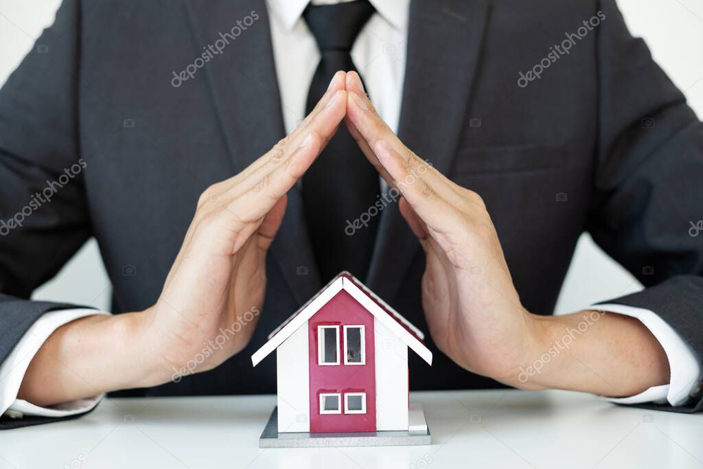The house is covered by the hands of a real estate agent to protect the house for customers, homebuyers, insurance, ready give to with new owner. Real estate Home insurance concept.