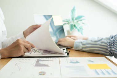 İki iş lideri çizelgeler, finansal grafikler hakkında konuşuyor. Sonuçları gösteren planlama stratejilerini analiz ediyor ve hesaplıyor. Ticari başarı oluşturma süreçlerini de..