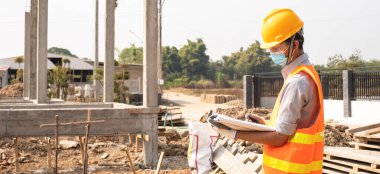 İnşaat alanında çalışan erkek mühendis veya mimar açık hava inşaat çalışmalarını inceliyor ve inceliyor..