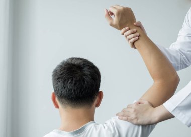 Kadın fizyoterapistler, erkek hastalara omuz sakatlığı olan hastalar için rehabilitasyon merkezinde omuzlarına masaj yapıyorlar. Fizyoterapi kavramları.