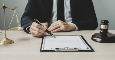 Profesyonel erkek avukatlar bir hukuk bürosunda çalışır. Teraziler, adalet terazileri, yargıç tokmağı ve dava belgeleri vardır. Hukuk ve adalet kavramları.