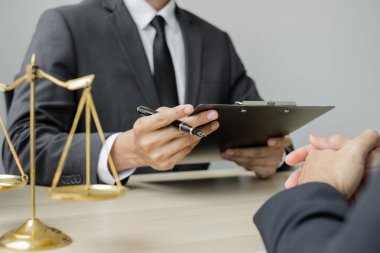 Bir erkek avukat ya da bir yargıç müvekkillerine yargı adaleti ve kovuşturma hakkında ölçekli danışmanlık yapıyor..