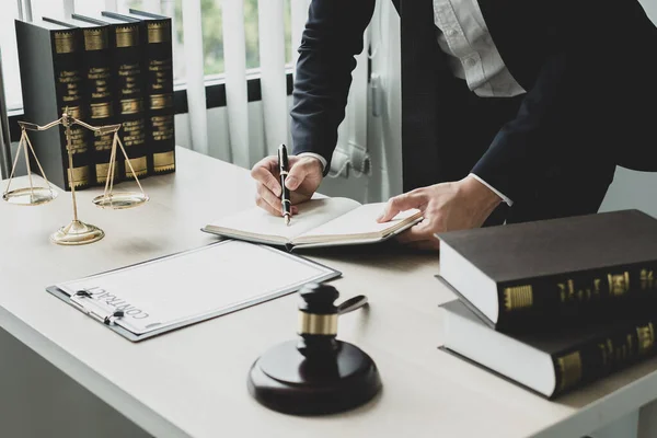 Profesyonel erkek avukatlar bir hukuk bürosunda çalışır. Teraziler, adalet terazileri, yargıç tokmağı ve dava belgeleri vardır. Hukuk ve adalet kavramları.