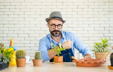 An elderly man wearing glasses is happy with tree care and decoration. It is a hobby of home gardening, living happily after retirement.