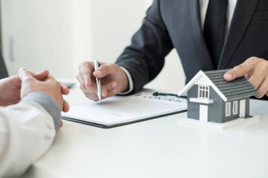 Ev modeli olan bir emlakçı ev sigortası almak için müşterilerle konuşuyor. Gayrimenkul Ev Sigortası.