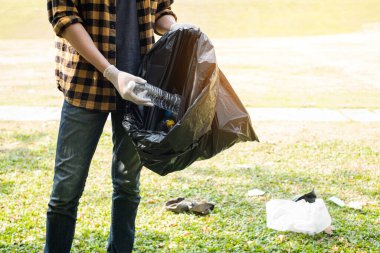 Adamın elleri plastik şişeleri topluyor, çöpleri siyah çöp torbalarına doldurup parkları temizliyor, kirlilikten kaçınıyor, çevreye ve ekosisteme dost oluyor..