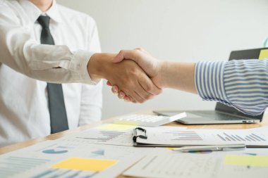 İki iş lideri çizelgeler, finansal grafikler hakkında konuşuyor. Sonuçları gösteren planlama stratejilerini analiz ediyor ve hesaplıyor. İş başarısı oluşturma süreçleri ve el sıkışıyor..