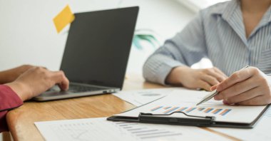 İki iş lideri çizelgeler, finansal grafikler hakkında konuşuyor. Sonuçları gösteren planlama stratejilerini analiz ediyor ve hesaplıyor. Ticari başarı oluşturma süreçlerini de..