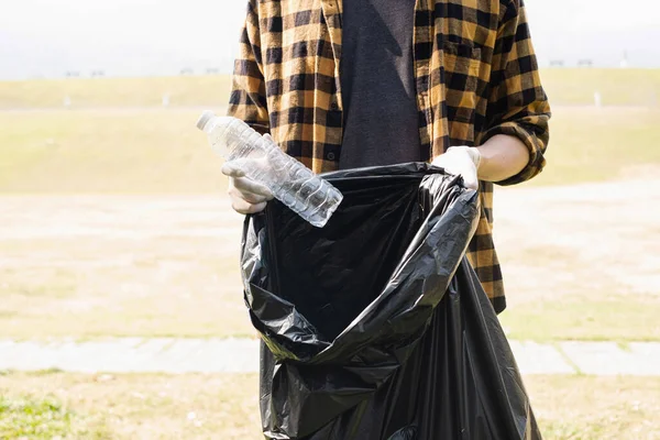 人の手はプラスチックボトルを拾い 公園できれいにするために黒いゴミ袋にゴミを入れ 汚染を避け 環境と生態系に優しいこと — ストック写真