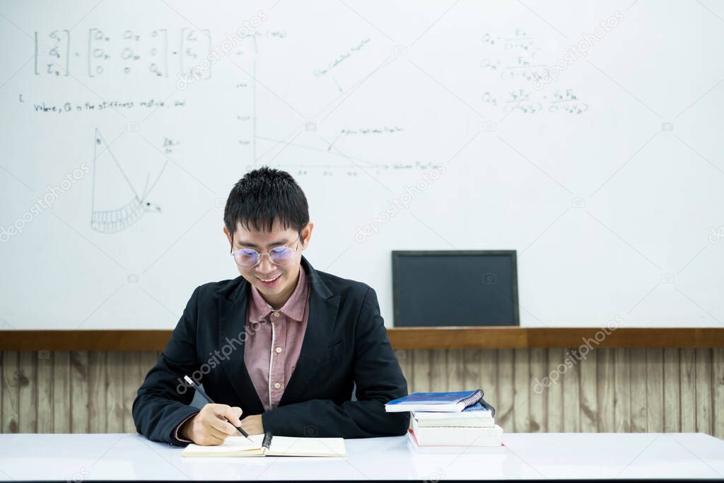 An Asian male teacher at the university is preparing lessons to teach in the classroom.