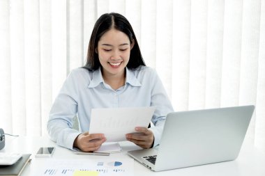 Asyalı kadın muhasebeci masalarında oturup yatırımlarıyla ilgili sonuçları gösteren mali grafikleri hesaplar ve başarılı bir iş büyüme süreci planlar..