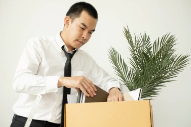 Bir erkek ofis çalışanı, karton kutulara bir şeyler dolduran bir şirketten kovulmaktan memnun değildir. Genç adam kovulduğu için stresliydi ve hayal kırıklığına uğradı. İşten çıkarma ve işsizlik kavramı.