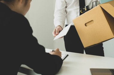 Umutsuzca kovulan bir ofis çalışanı işverenine istifa mektubunu verir ve eşyalarını karton kutu konseptine koyar..