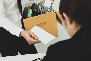 Umutsuzca kovulan bir ofis çalışanı işverenine istifa mektubunu verir ve eşyalarını karton kutu konseptine koyar..