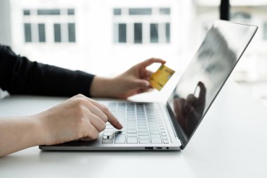 İş kadınlarının eli bir kredi kartı tutuyor ve online alışveriş ve internet ödemeleri için dizüstü bilgisayar kullanıyor.