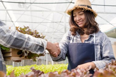Hidrofonik, başarılı pazarlıklardan sonra erkek müşterilerle tokalaşan dişi bir çiftçi. Organik tarım sektörü kavramı.