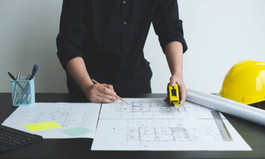 İnşaatta çalışan mimarlar ya da mühendisler inşaat planları, baskı, inşaat sahalarında yazılar çiziyor. Ev tasarımı kavramı.