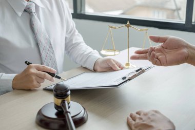 Bir erkek avukat ya da yargıç müvekkillerine adalet ve kovuşturma konusunda danışmanlık yapıyor. Teraziler, yargıç tokmağı, yasal belgeler, yasal hizmetler kavramı..