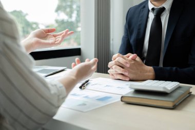 İki iş lideri çizelgeler, finansal grafikler hakkında konuşuyor. Sonuçları gösteren planlama stratejilerini analiz ediyor ve hesaplıyor. Ticari başarı oluşturma süreçlerini de..