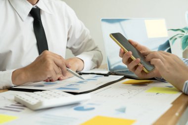 İki iş lideri çizelgeler, finansal grafikler hakkında konuşuyor. Sonuçları gösteren planlama stratejilerini analiz ediyor ve hesaplıyor. Ticari başarı oluşturma süreçlerini de..