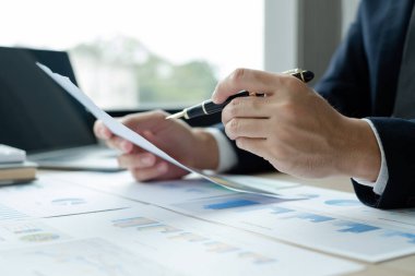 İş adamının eli masalarında oturup yatırımlarıyla ilgili sonuçları gösteren finansal grafikleri hesaplıyor, başarılı bir iş büyüme süreci planlıyor.