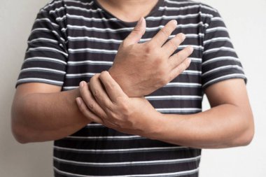 Bileğinde ağrı ve uyuşukluk olan bir adamın elinde acı ve sinir uçlarında karıncalanma vardır. Bu da Guillain-Barre Sendromu 'nun COVID-19' a karşı aşılandıktan sonraki yan etkisi..