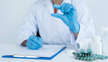 Kadın bir bilim adamı ya da bir tıp uzmanı farklı haplardan bir numune bulundurur. Tıbbi ve sağlık hizmetleri kavramının kimyasal uyuşturucu formülasyonlarına tanı koymak için.