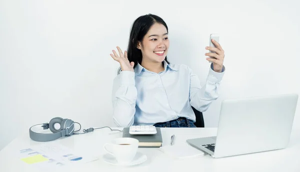 一位年轻的亚洲女人一边看着数码智能手机屏幕 一边通过在线视频远距离交流 高兴地与一位朋友打招呼 — 图库照片