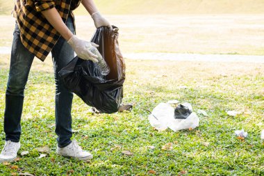 Adamın elleri plastik şişeleri topluyor, çöpleri siyah çöp torbalarına doldurup parkları temizliyor, kirlilikten kaçınıyor, çevreye ve ekosisteme dost oluyor..