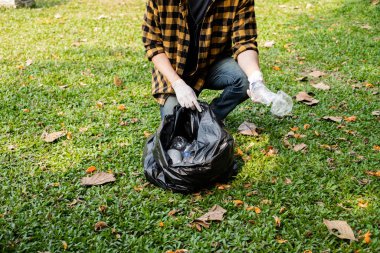 Adamın elleri plastik şişeleri topluyor, çöpleri siyah çöp torbalarına doldurup parkları temizliyor, kirlilikten kaçınıyor, çevreye ve ekosisteme dost oluyor..