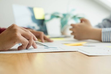 İki iş lideri çizelgeler, finansal grafikler hakkında konuşuyor. Sonuçları gösteren planlama stratejilerini analiz ediyor ve hesaplıyor. Ticari başarı oluşturma süreçlerini de..