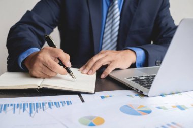 Evde çalışan ve yatırımlarının sonuçlarını gösteren mali grafikleri hesaplayan iş adamının el emeği, iş büyümesinin adımlarını planlamak..