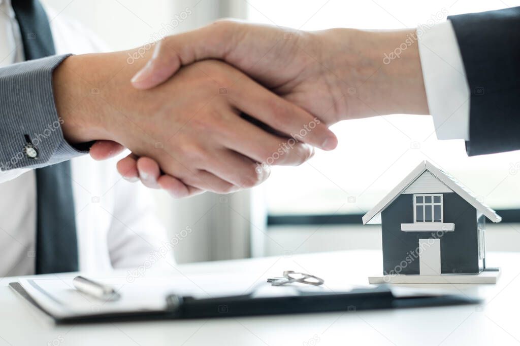 Businessmen and brokers' real estate agents shake hands after completing negotiations to buy houses insurance and sign contracts. Home insurance concept.