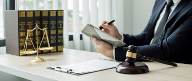 Profesyonel erkek avukatlar bir hukuk bürosunda çalışır. Teraziler, adalet terazileri, yargıç tokmağı ve dava belgeleri vardır. Hukuk ve adalet kavramları.