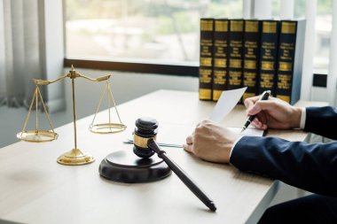 Profesyonel erkek avukatlar bir hukuk bürosunda çalışır. Teraziler, adalet terazileri, yargıç tokmağı ve dava belgeleri vardır. Hukuk ve adalet kavramları.