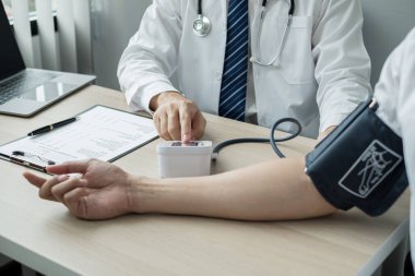 Erkek doktorlar kan basıncını ölçtü, hasta kalp atışlarını inceledi ve sağlık hizmetleri hakkında yakından konuştu. Tıbbi ve sağlık hizmetleri kavramları.