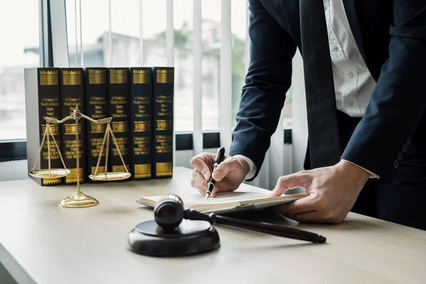 Profesyonel erkek avukatlar bir hukuk bürosunda çalışır. Teraziler, adalet terazileri, yargıç tokmağı ve dava belgeleri vardır. Hukuk ve adalet kavramları.