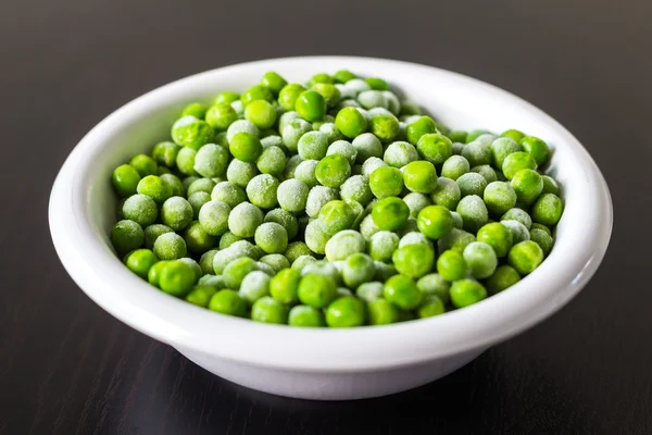 Un bol blanc avec des petits pois verts surgelés dans la cuisine Photos De Stock Libres De Droits