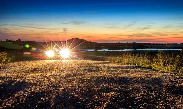 Auto met fel licht in mooie berg landschap zonsondergang zon — Stockfoto