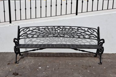 İspanya 'da Estepona' da sessiz bir kilise avlusunda süslü demirden bir deseni olan metal bir umumi koltuk.