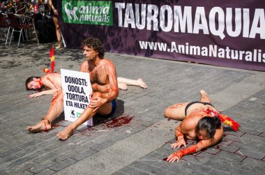 San Sebastin, Bask Ülkesi - 12 Ağustos 2012. Son derece etkili bir sokak protestosu. Üç kişi yalan söylüyor ya da yerde oturuyor, yarı çıplak, sahte kanla kaplı, ciddi yaralanma taklidi yapıyor..