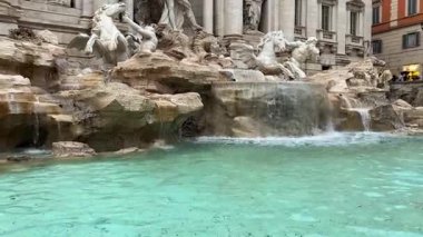 Roma, İtalya, 10 Kasım 2023. Roma 'daki Trevi Çeşmesi, ön plandaki turkuaz suyu, kaya oluşumlarının üzerindeki şelaleleri ve sarayın Barok cephesine entegre olmuş anıtsal mermer heykelleri gösteriyor..