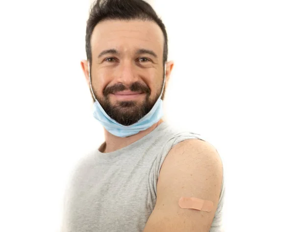 Gülümseyen aşılanmış adam yamayla kolunu gösteriyor.