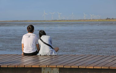 Beyaz gömlekli genç bir çift ve gölün arka planında mavi gökyüzü olan bir kadın.