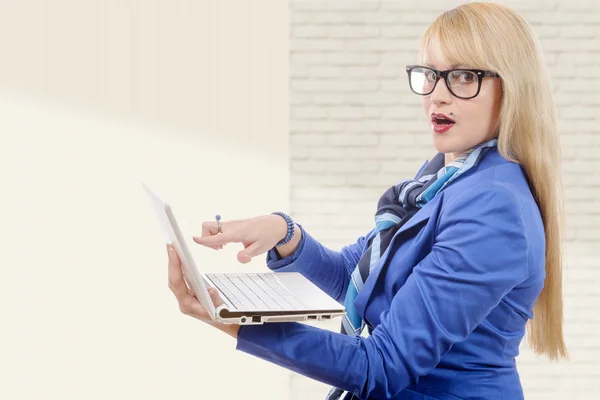 Jonge mooie zakenvrouw in blauwe pak met laptop in het kantoor — Stockfoto