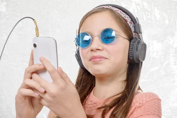 Nedospělý dívka poslechu hudby s jeho smartphone, na bílém pozadí — Stock fotografie