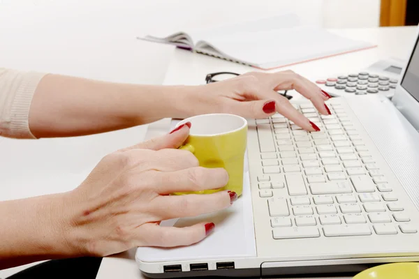 Primo piano di mano di donna con tazza di caffè sulla scrivania — Foto Stock
